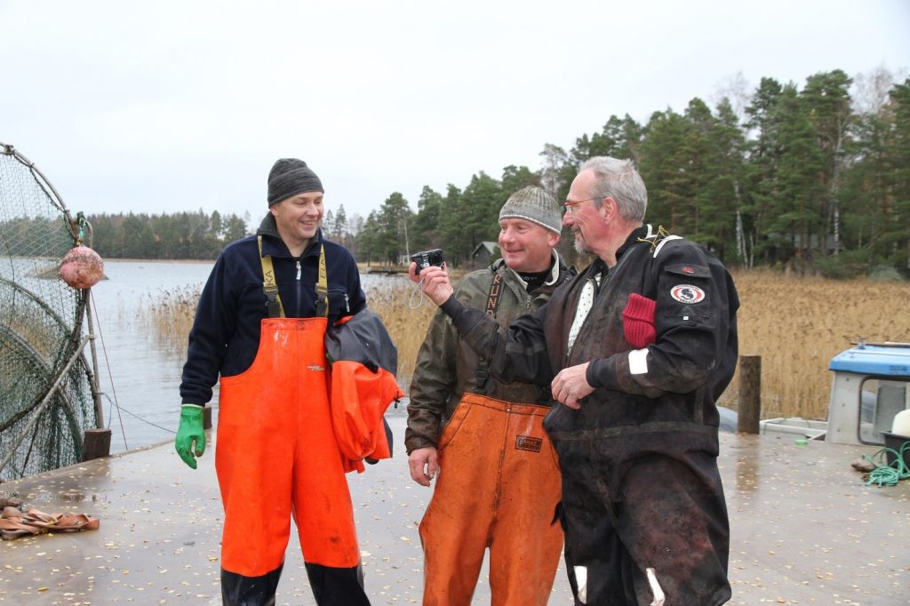   EU-parlamentariker Nils Torvalds var förbundets och Nylands Fiskarförbunds gäst 28.10.2013. Torvalds visar Krister Hellström och Mikael Lindholm vilka bilder fastnat i kameran under fiskefärden. Torvalds jobbade aktivt för att sälersättningarna togs med i havs- och fiskerifondens åtgärder. Bild: Kim Jordas.